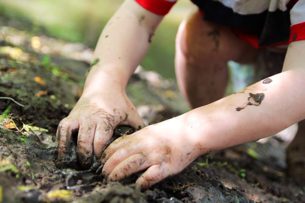 young child hands picking up wet mud