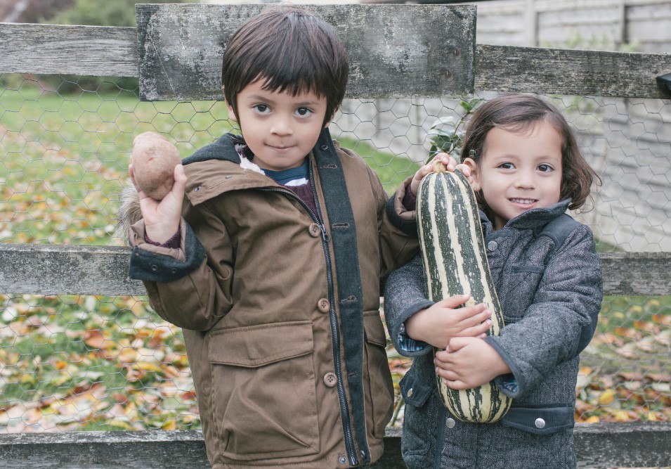 boy holding potato and girl hodling homegrown marrow