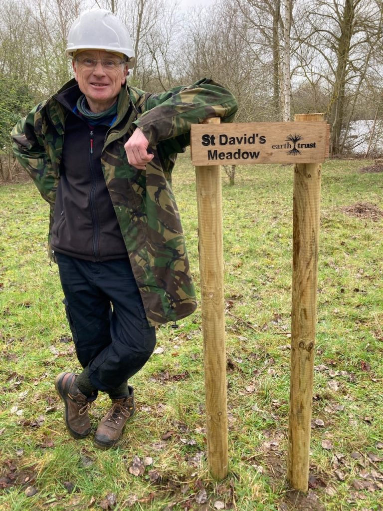 man leaning on wooden signpost which reads St David's Meadow