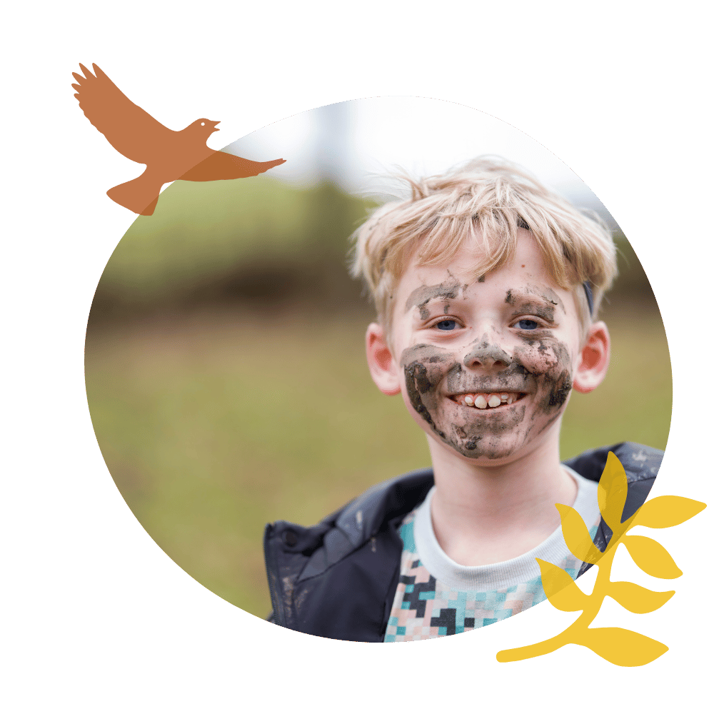 Boy with mud on his face smiling.